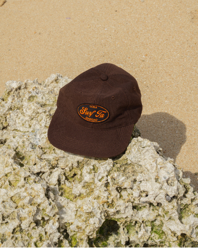 Brown cap with a logo on a rock at the beach