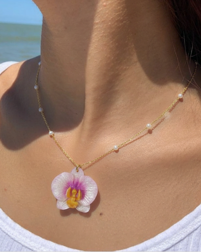 Necklace with a white orchid  pendant worn by a model