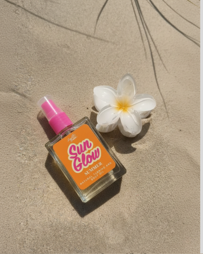 Sun Glow sun tanning lotion bottle with a white flower on sand