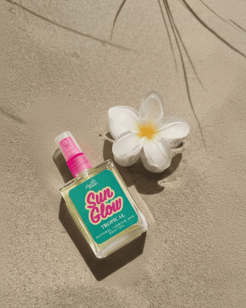Sun Glow tropical sun spray bottle with a white flower on sand