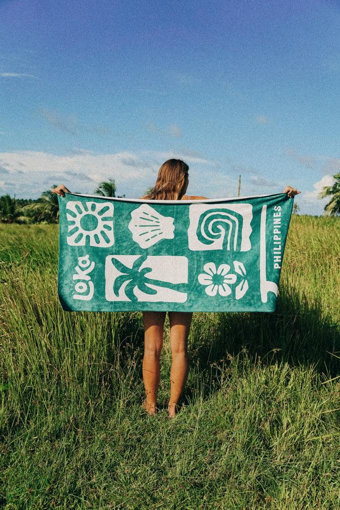 Female model holding a Loka Sundrenched towel from on the On Cloud 9 Collection