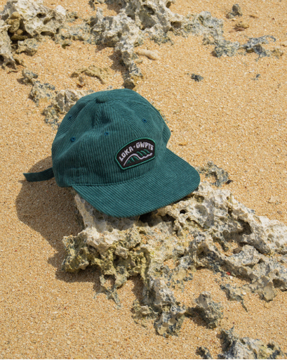 Green cap with a logo on a sandy surface